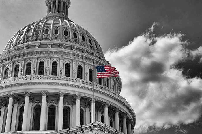 American flag waving in front of the US Capitol building